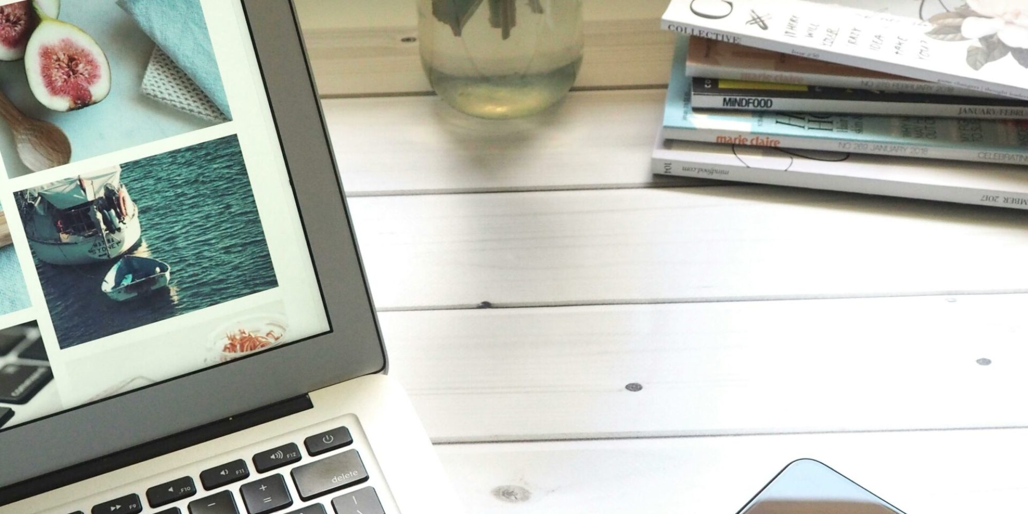 Elegant workspace featuring a laptop, smartphone, and fresh roses in a bright setting.