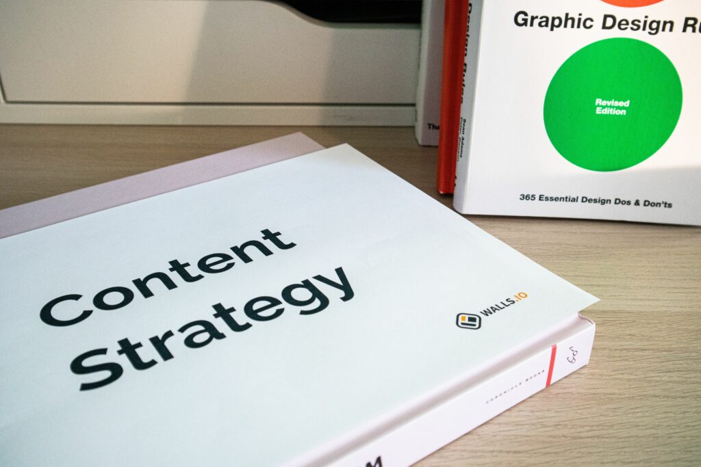 Books on content strategy and graphic design essentials resting on a wooden desk.