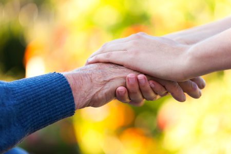 Young female hand holding an old man's hand.